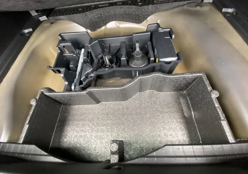 Coffre ouvert d'une Peugeot 2008 gris foncé, montrant le rangement sous plancher avec outils de bord.