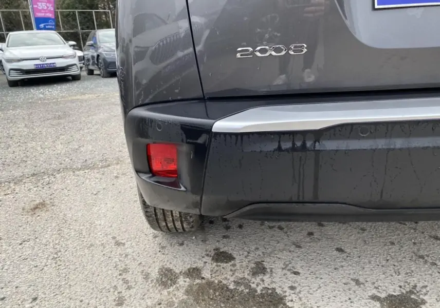 Gros plan sur le coin arrière gauche d'un Peugeot 2008 gris foncé montrant le feu arrière rouge et le logo 2008.