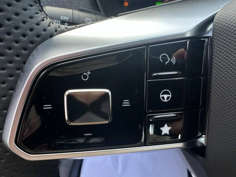 Gros plan sur les commandes au volant noir et argenté du MG ZS Hybrid+ 2025, avec boutons multifonctions et cuir perforé.