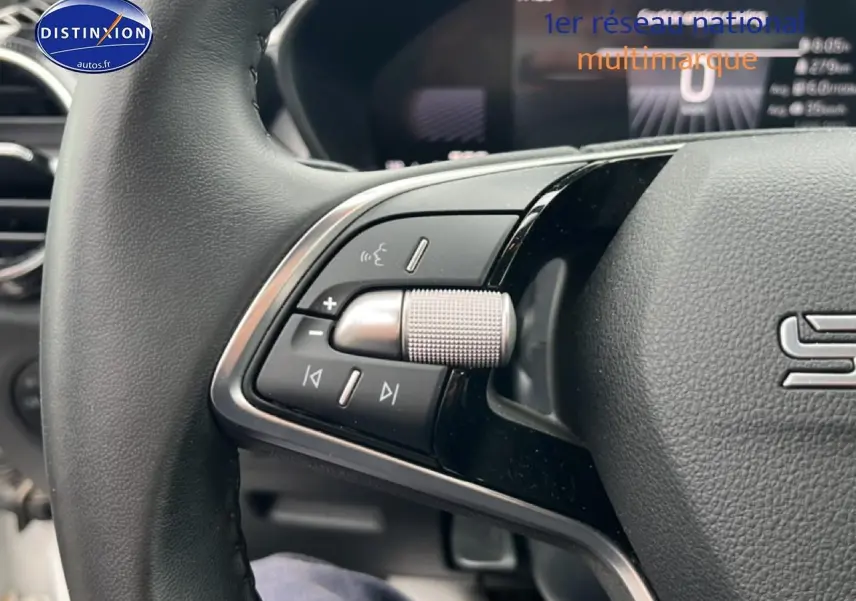 Gros plan sur les commandes gauche du volant cuir multifonction d’une Skoda Fabia blanche 2025, avec molette argentée.
