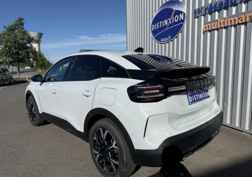 Vue 3/4 arrière droite d'une Citroën C4 Hybrid blanche Okenite avec toit noir brillant et feux arrière LED distinctifs.