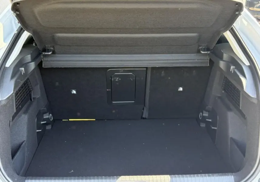 Coffre ouvert vu de l'arrière d'une Citroën C4 Hybrid 145 ch blanc Okenite, espace de chargement vide et propre.