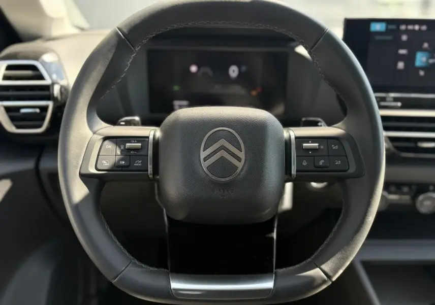 Vue rapprochée du volant en cuir noir avec commandes intégrées de la Citroën C4 Hybrid 2025.