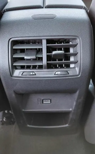 Vue rapprochée de la console centrale arrière noire de l'Opel Astra 2025, avec ventilation et port USB visibles.