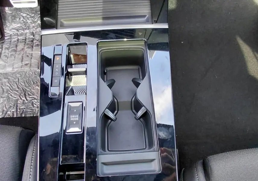 Vue plongeante sur la console centrale noire brillante de l’Opel Astra 2025 avec sélecteur de mode de conduite et porte-gobelets.