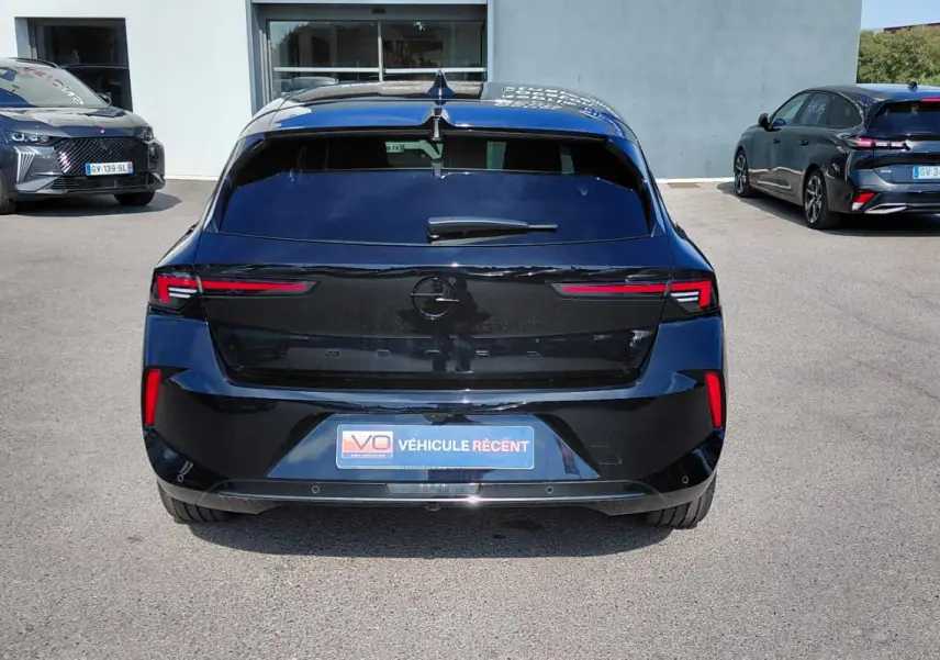 Vue arrière d'une Opel Astra noire 2025 avec feux LED fins et vitres surteintées, stationnée en extérieur.