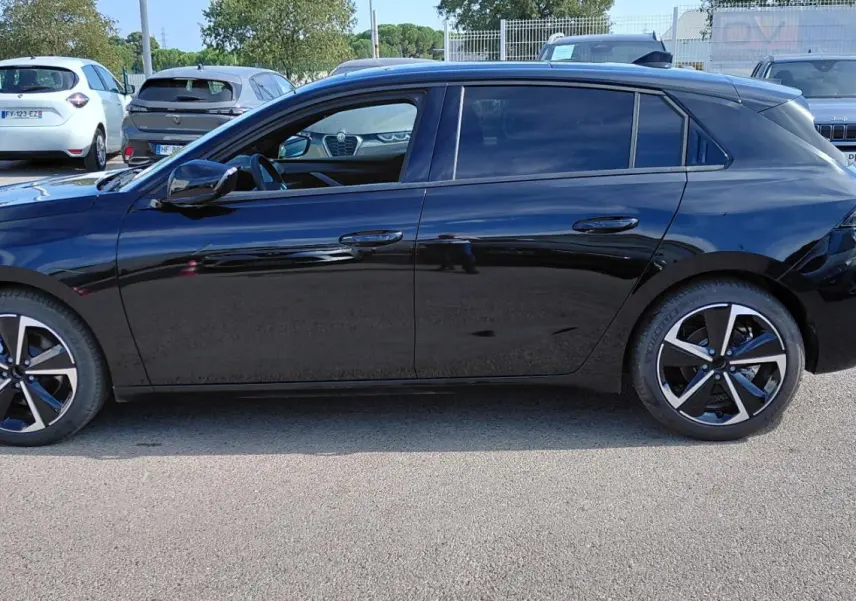 Opel Astra noire vue de profil côté gauche, avec vitres surteintées et jantes alliage 17 pouces.