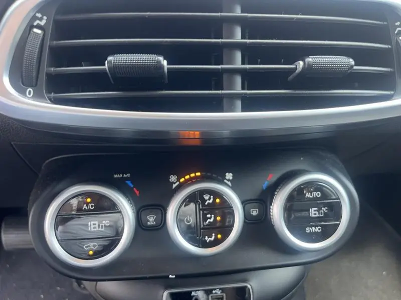 Gros plan sur la console de climatisation automatique bi-zone de la FIAT 500X bronze Magnetico, avec affichage digital et commandes rotatives.