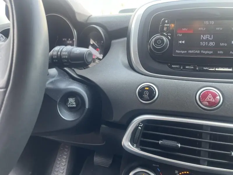 Intérieur du tableau de bord de la Fiat 500X bronze, avec bouton start/stop, écran tactile et commandes centrales visibles.