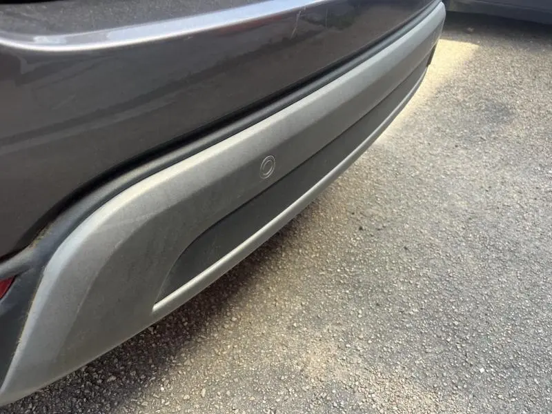 Gros plan sur le pare-chocs arrière gris foncé du Fiat 500X 2015 avec capteur de stationnement intégré.