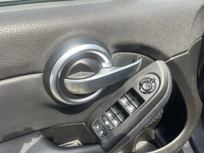 Poignée de porte intérieure côté conducteur en plastique noir avec commandes électriques sur FIAT 500X bronze métallisé 2015.