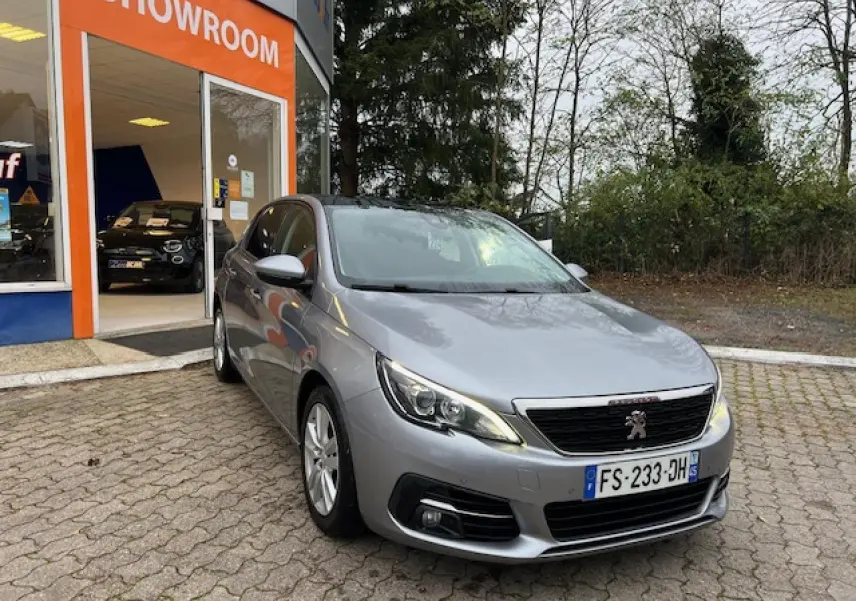 Peugeot 308 gris artense vue 3/4 avant droit devant un showroom avec toit panoramique en verre.