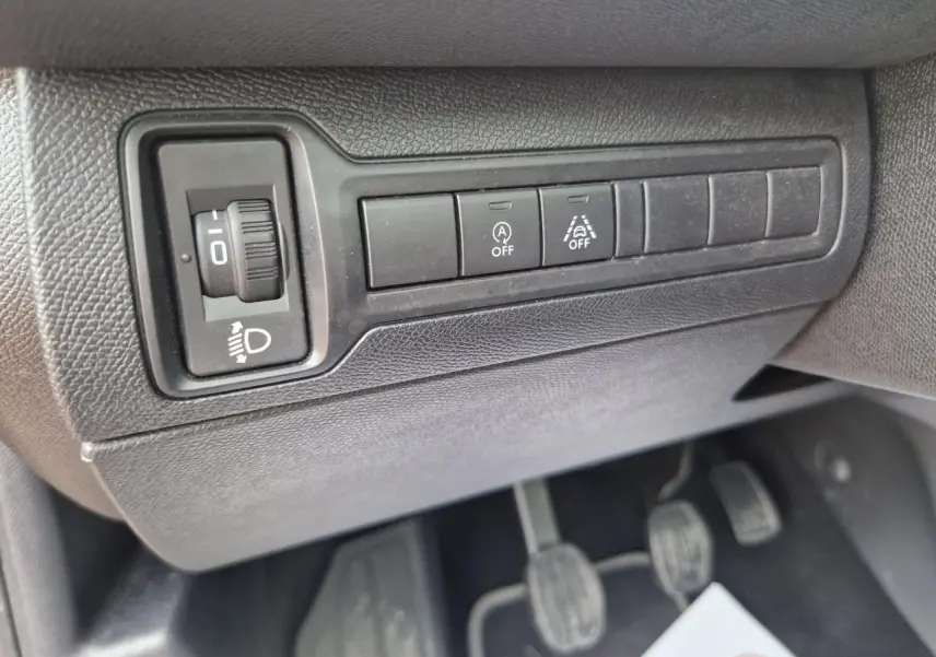 Gros plan sur les commandes d'éclairage et d'assistance au conducteur dans l'habitacle d'une Peugeot 308 1.2i gris artense.