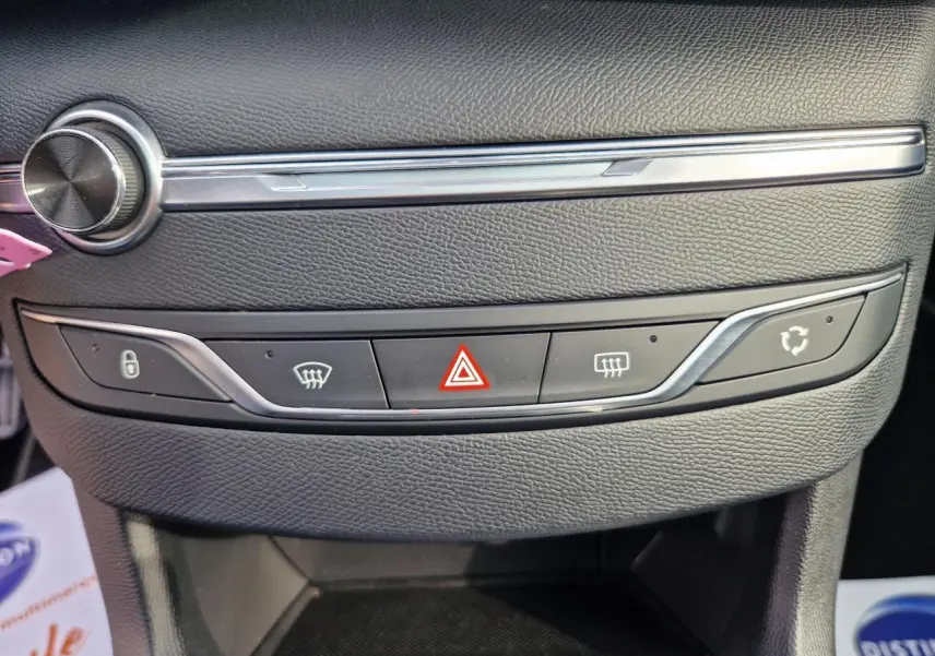 Gros plan sur la console centrale noire de la Peugeot 308 gris artense, avec boutons de verrouillage et alerte triangle rouge.