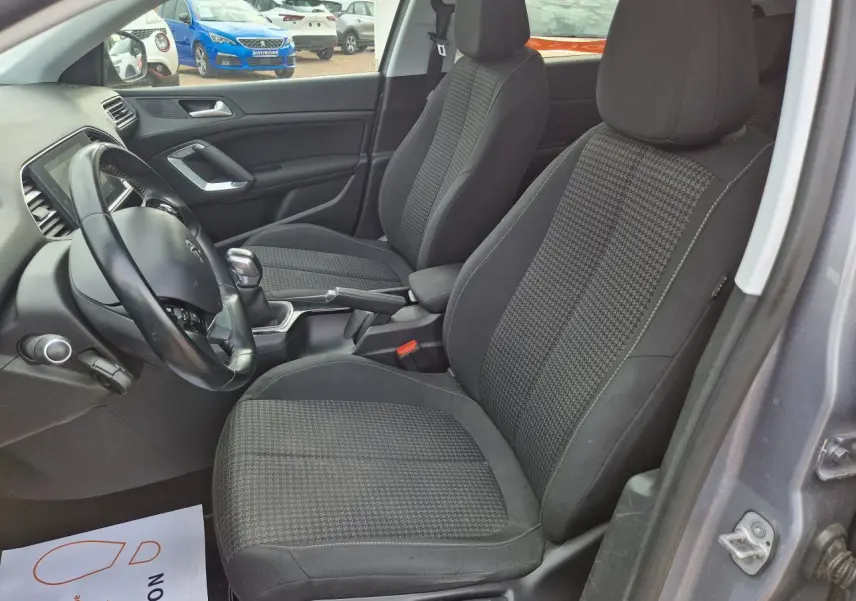Intérieur de la Peugeot 308 gris artense, vue côté gauche montrant les sièges avant et le volant noir.