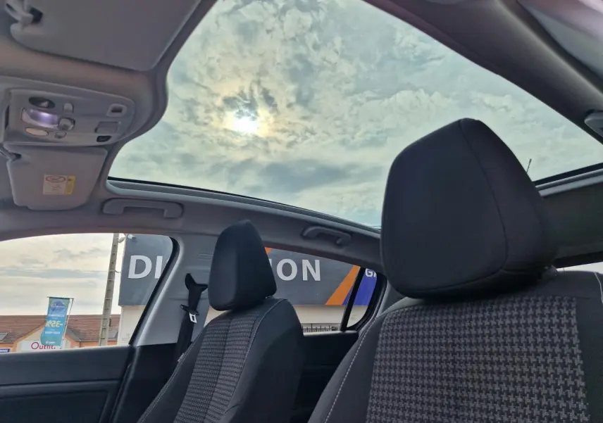 Intérieur de la Peugeot 308 2018 avec toit panoramique en verre et sièges avant en tissu noir à motifs.