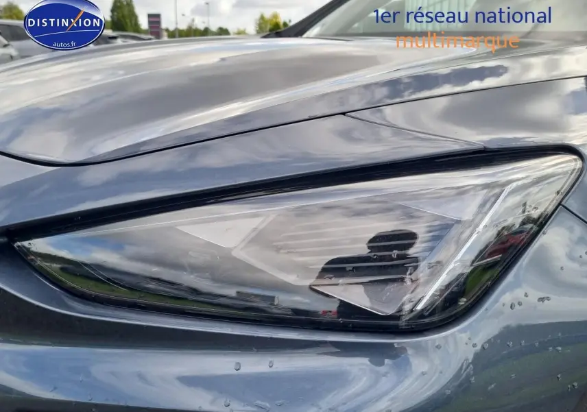 Gros plan sur le phare avant droit du CUPRA Formentor 2025 en gris magnétique avec reflets et gouttes d'eau visibles.