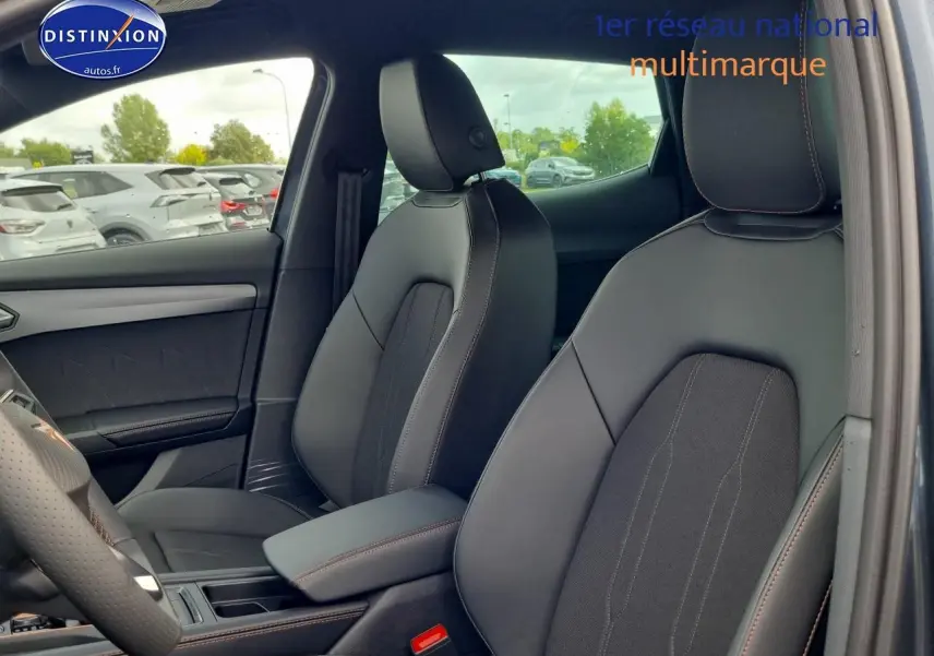 Intérieur avant du CUPRA Formentor 1.5 eTSI hybride 2025, sièges sport noirs avec surpiqûres marron et accoudoir central.