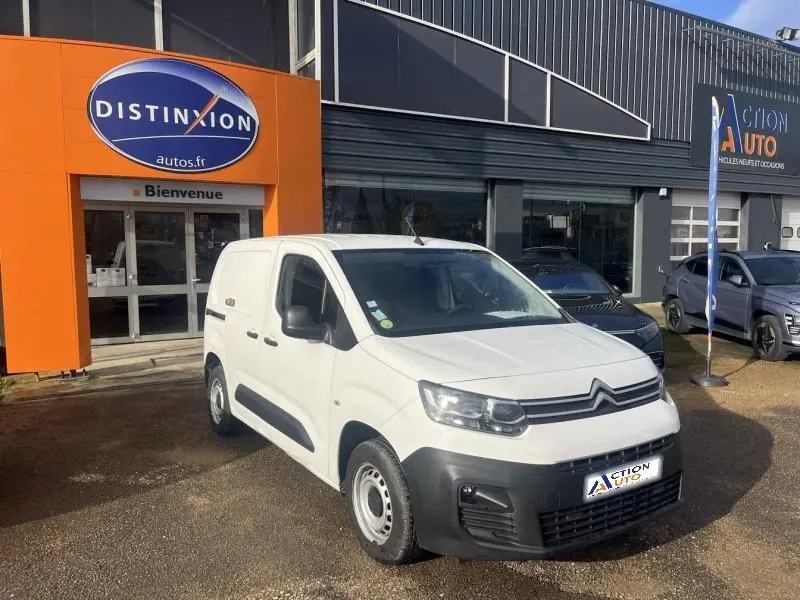 Citroën Berlingo Fourgon blanc banquise vu en 3/4 avant droit devant un garage avec enseigne orange.