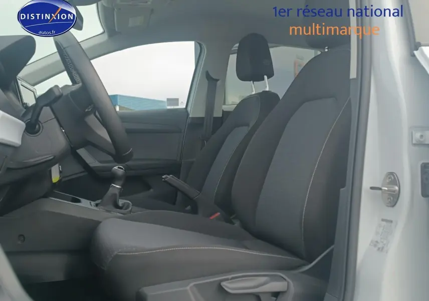 Vue intérieure côté conducteur de la SEAT Ibiza blanc Nevada 2025, sièges tissu gris et volant cuir méplat.