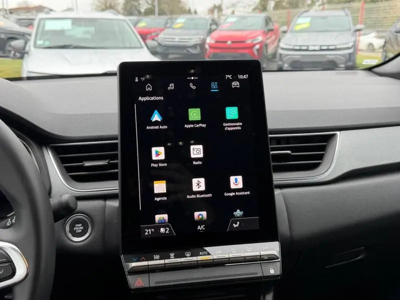 Vue intérieure centrée sur l'écran tactile du tableau de bord du Renault Captur 2025, avec commandes climatisation visibles.