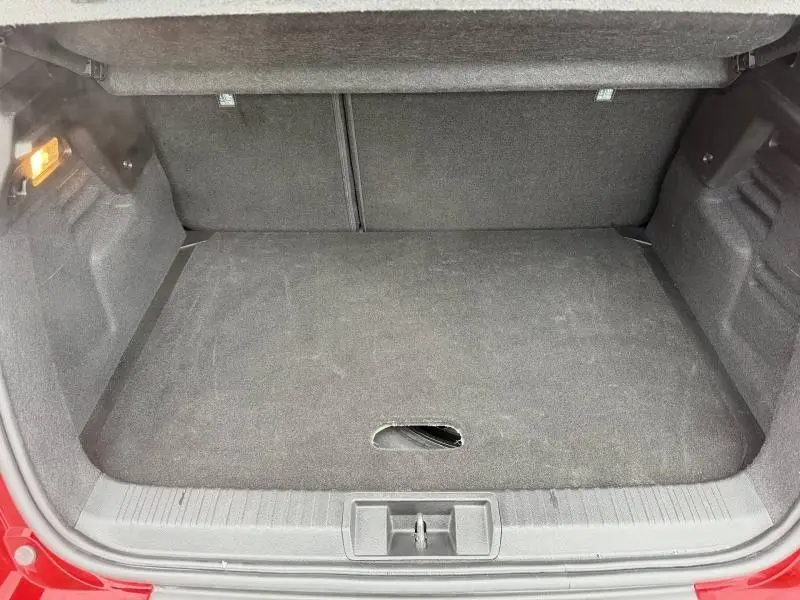 Coffre ouvert du Renault Captur 2025 Rouge Flamme, vue intérieure montrant l’espace de chargement vide et la moquette noire.