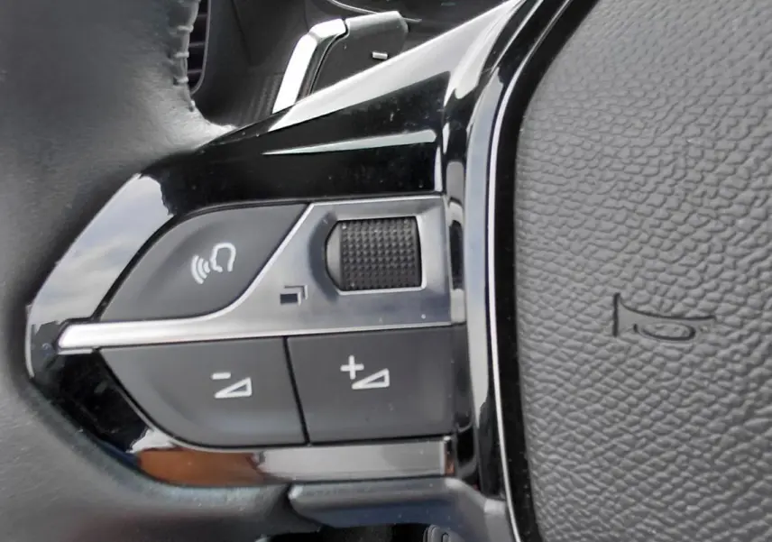 Détail du côté gauche du volant noir du Peugeot 2008 Hybrid 145 e-DCS6 Style 2025 montrant les commandes audio.