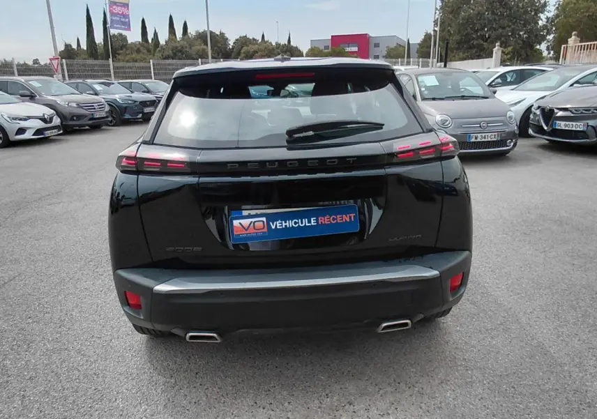 Vue arrière d’un Peugeot 2008 Hybrid 145 noir 2025, avec feux arrière LED et double sortie d’échappement visible.