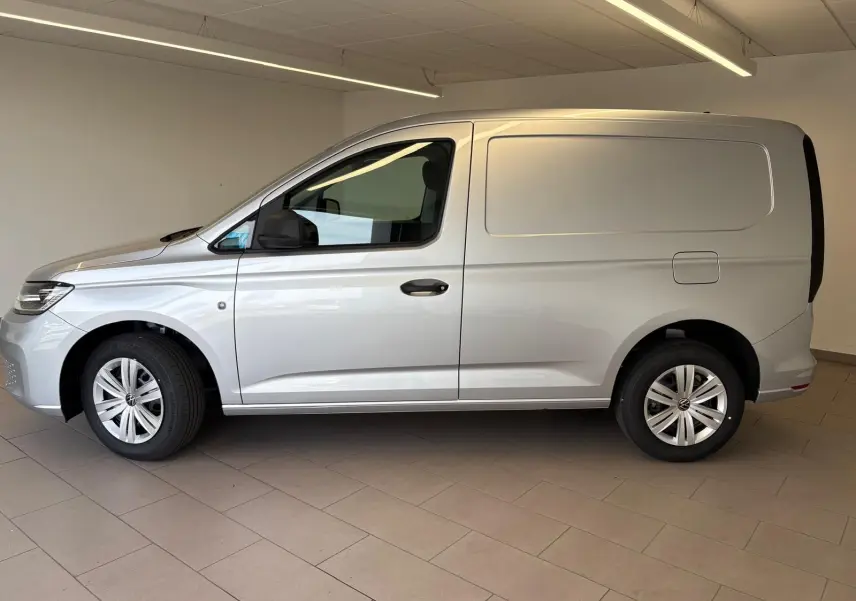 Vue de profil côté gauche du Volkswagen Caddy 1.5 TSI Business 2025 en gris argent, fourgon compact sans vitres latérales arrière.