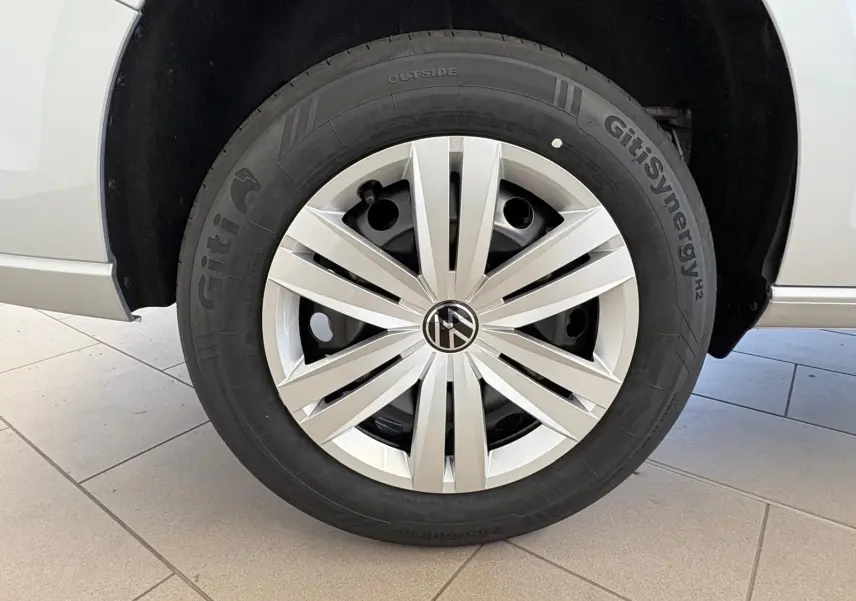 Gros plan sur la roue avant droite du Volkswagen Caddy gris argent 2025 avec jante en alliage et pneu GitiSynergy.