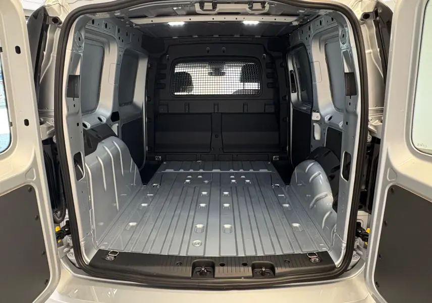 Vue arrière du Volkswagen Caddy 2025 gris argent, montrant l'espace de chargement vide et la cloison métallique séparant la cabine.