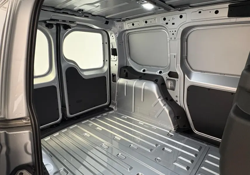 Intérieur de la zone de chargement du Volkswagen Caddy 2025 gris argent, vue depuis l'ouverture latérale droite.