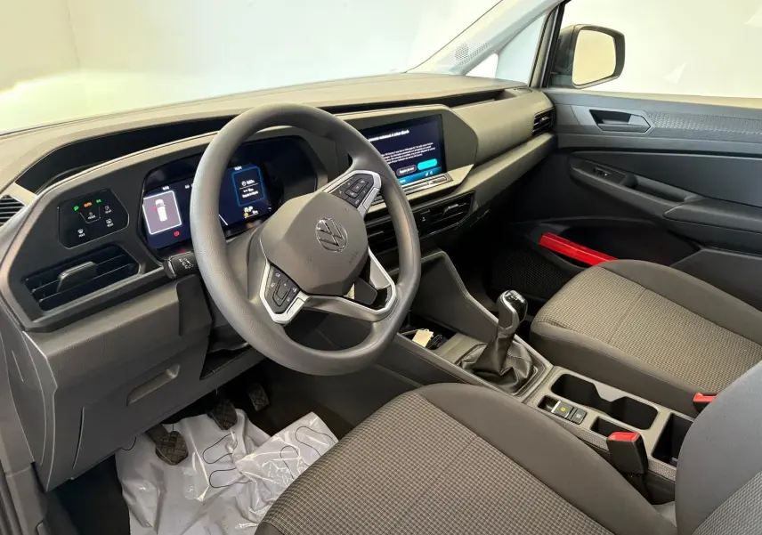 Intérieur du Volkswagen Caddy 2025 vu côté conducteur, tableau de bord moderne et levier de vitesse manuel gris argent.