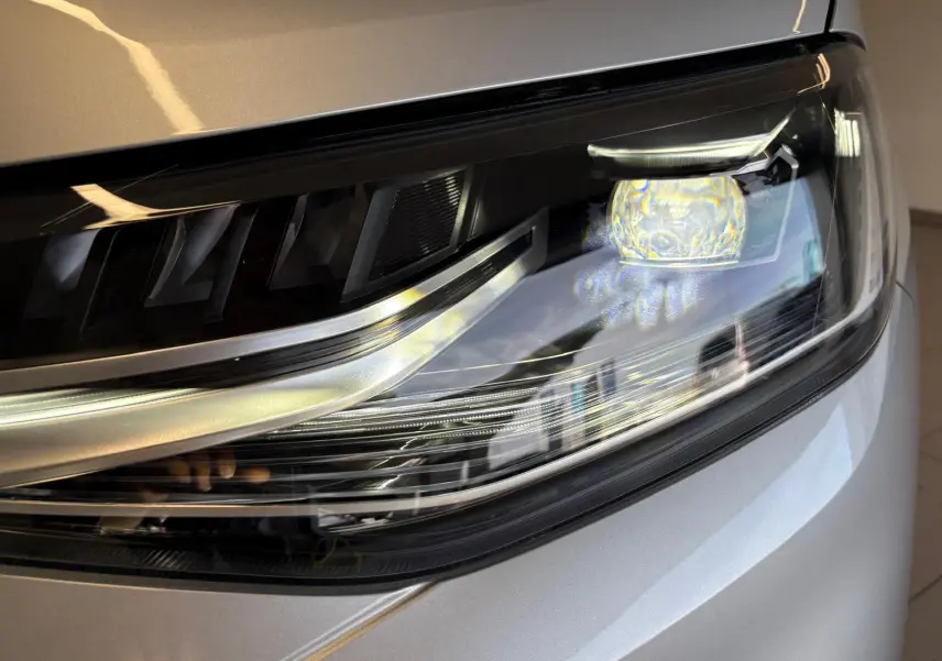 Gros plan sur le phare avant droit du Volkswagen Caddy 2025 gris argent, mettant en valeur son design moderne et lumineux.
