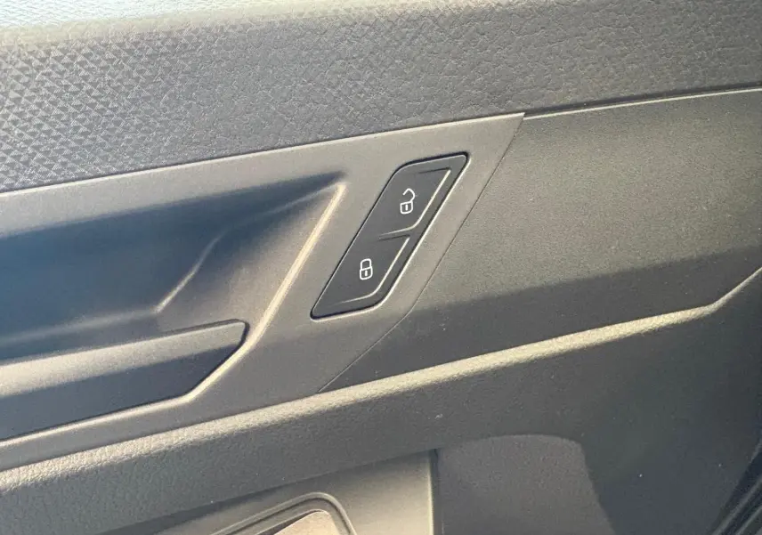 Gros plan sur la commande de verrouillage des portes côté intérieur d'une Volkswagen Caddy gris argent 2025.