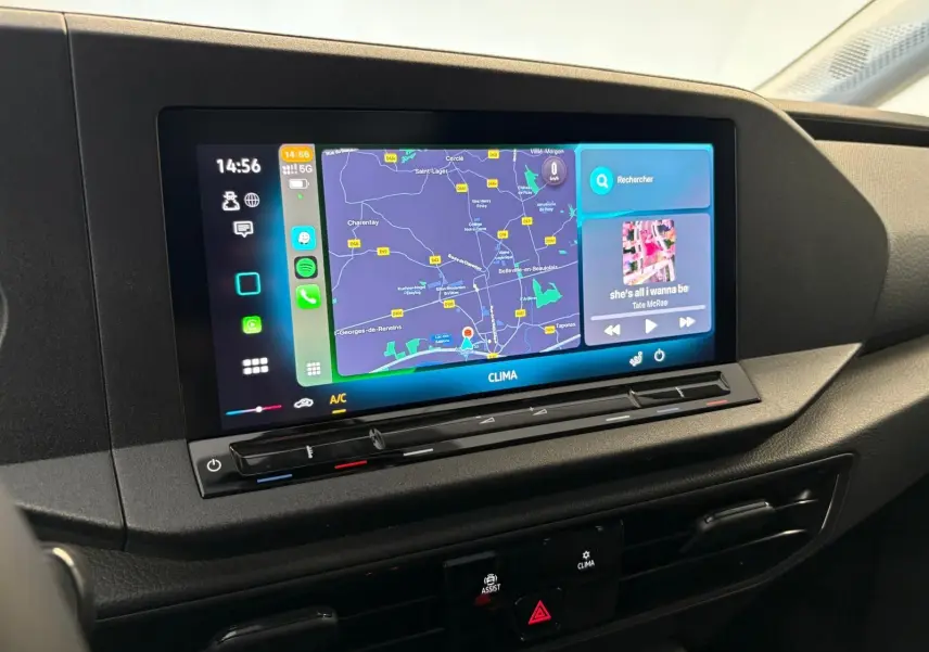 Écran tactile central du tableau de bord du Volkswagen Caddy 2025 gris argent, affichant la navigation et la musique.