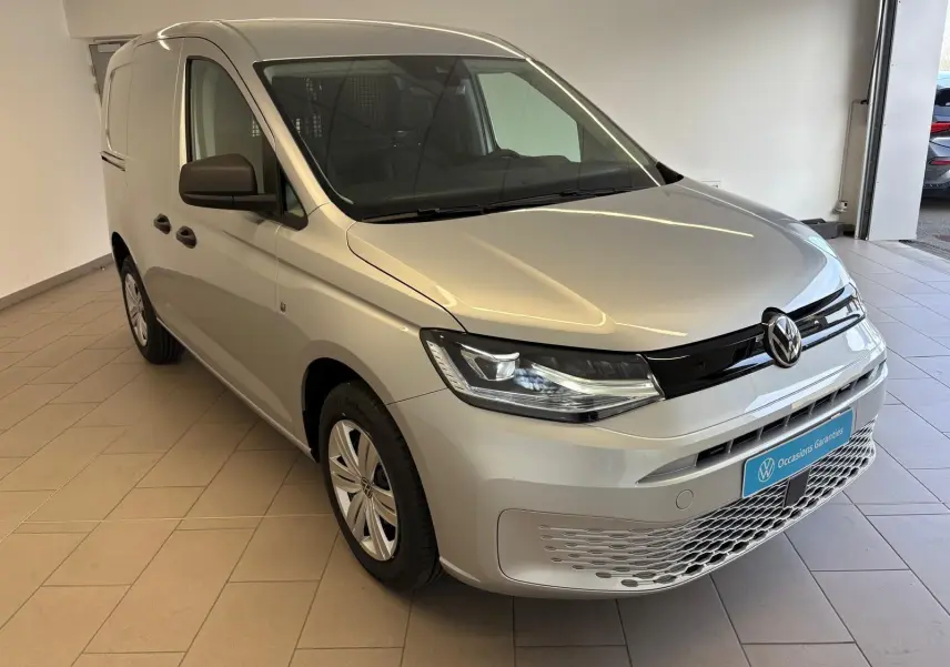 Vue 3/4 avant droite du Volkswagen Caddy 2025 gris argent avec calandre noire et phares modernes.