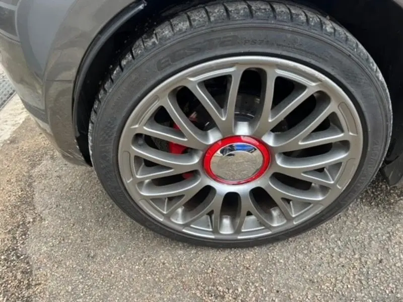 Gros plan sur la jante alu gris foncé à centre rouge de l'ABARTH 500 1.4 Turbo T-Jet 2013, roue avant droite.