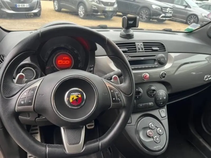 Intérieur de l'Abarth 500 2013 en gris foncé, vue du volant cuir sport et tableau de bord avec logo Abarth rouge.