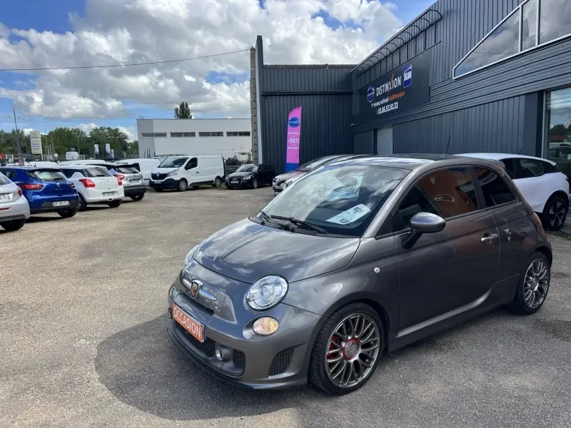Vue 3/4 avant droite d'une ABARTH 500 gris foncé métal avec jantes alliage et détails sportifs visibles.