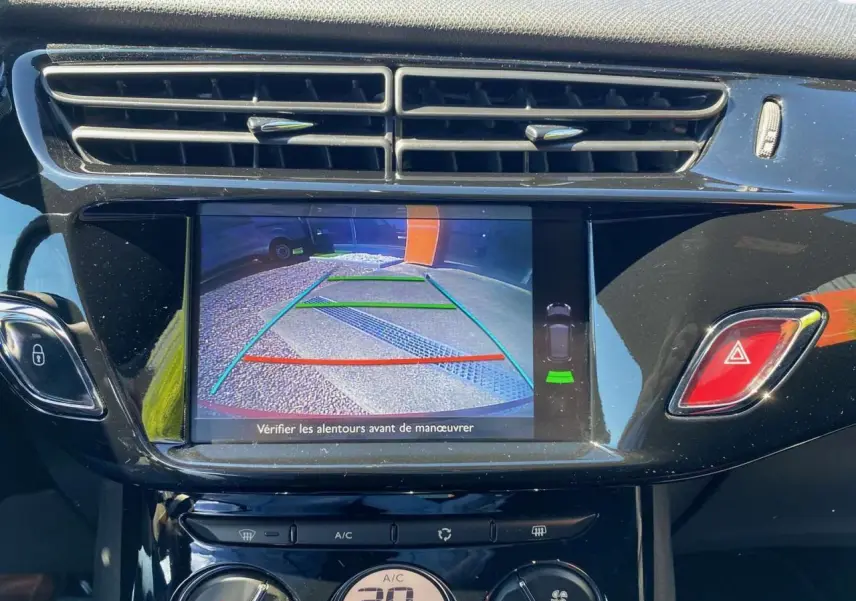 Écran tactile central affichant la caméra de recul dans l'habitacle d'une DS3 rouge toit blanc, tableau de bord noir brillant.