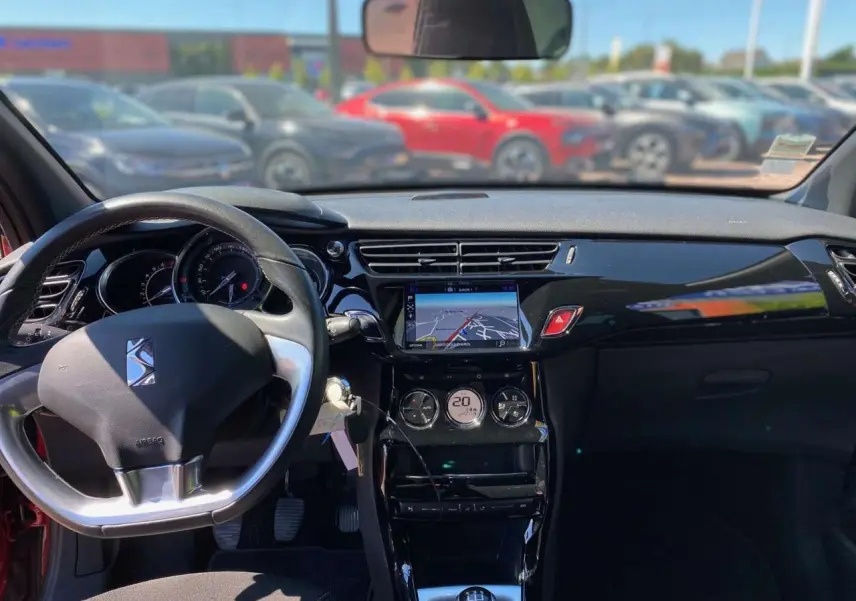 Vue intérieure avant du tableau de bord de la DS3 rouge avec toit blanc, affichage navigation tactile et volant DS.