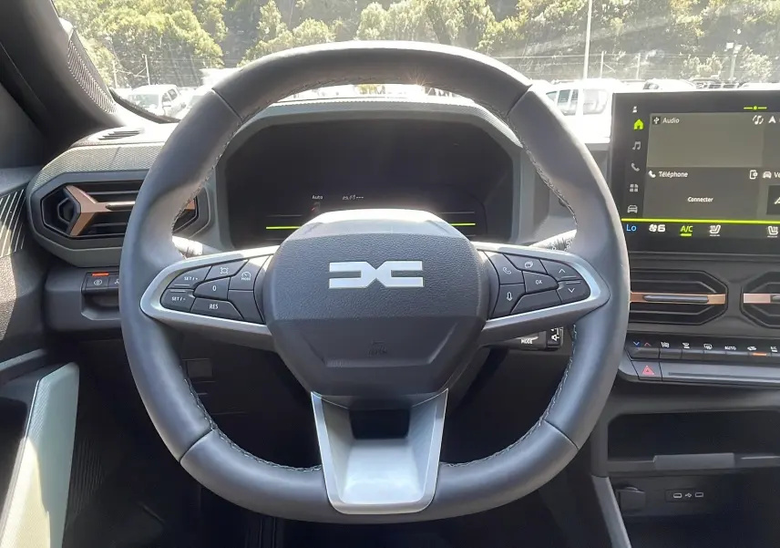 Vue rapprochée du volant multifonction du Dacia Duster 2025, avec tableau de bord numérique et écran tactile.