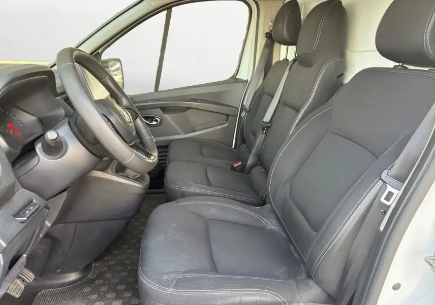 Vue intérieure côté conducteur du Renault Trafic Fourgon blanc 2022, sièges noirs avec surpiqûres grises et volant multifonction.