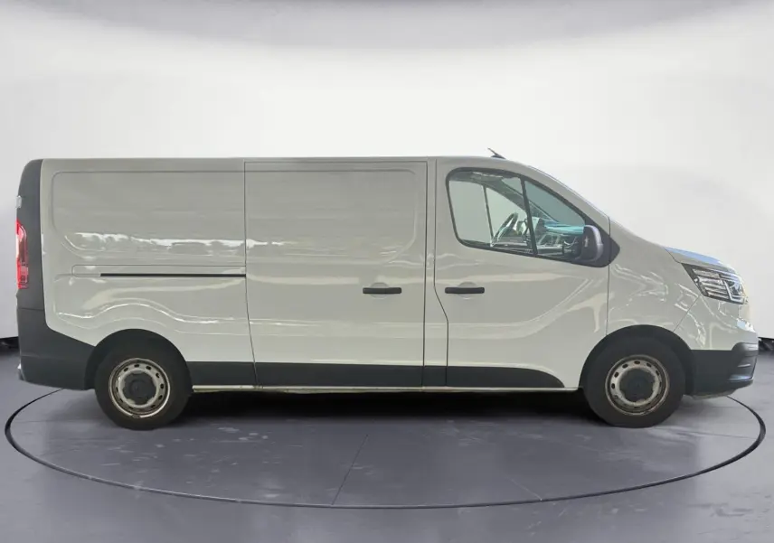 Profil côté droit d'un utilitaire Renault Trafic Fourgon blanc, version L2H1 3T, avec portes coulissantes et jantes acier.