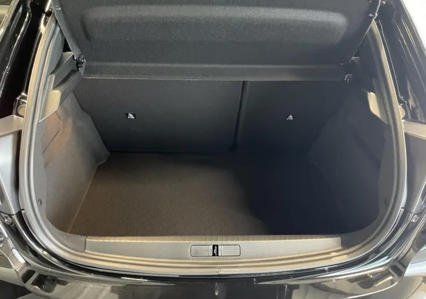 Coffre ouvert vu de face d’une Peugeot 208 noire, montrant un espace de chargement vide et propre.