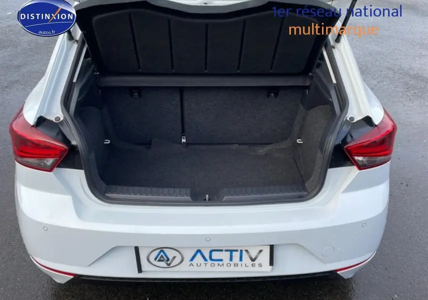 Vue arrière d’une SEAT Ibiza blanc Nevada 2025 avec coffre ouvert et feux arrière rouges visibles.