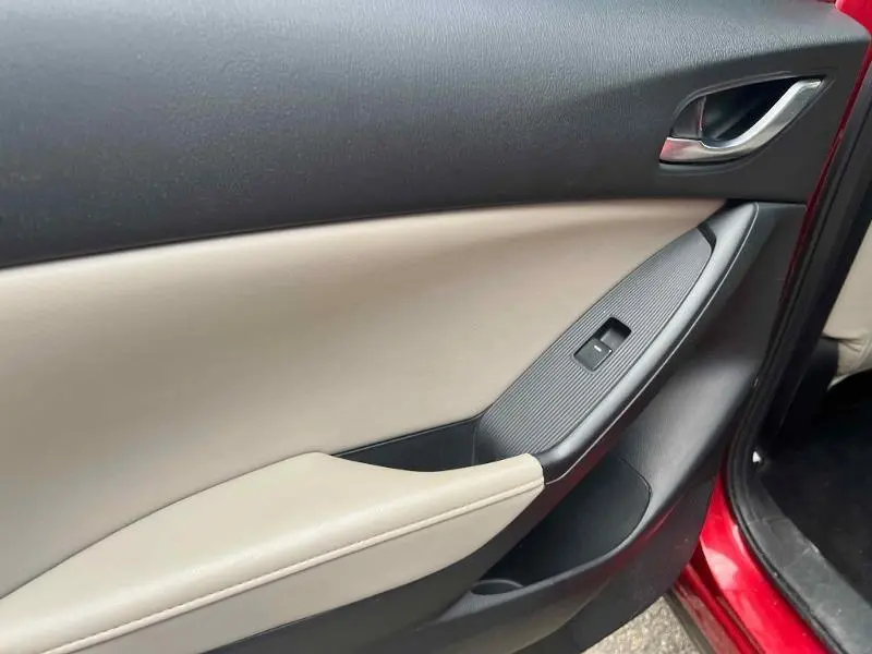 Vue rapprochée de la porte avant gauche beige et noire du Mazda CX-5 Soul Red Métallisé avec commande de fenêtre électrique.