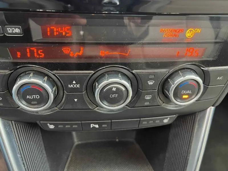 Vue rapprochée du tableau de bord du Mazda CX-5 2013, montrant les commandes de climatisation et l'affichage digital orange.