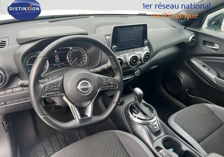 Vue intérieure côté conducteur du Nissan Juke 2024, montrant le volant, tableau de bord et console centrale en noir.